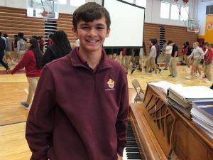 Scecina student Anthony Higgins stands by piano in Scecina gym
