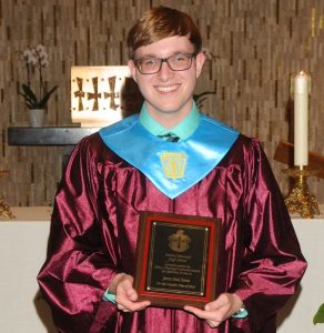 Student in cap and gown with Henninger Award plaque